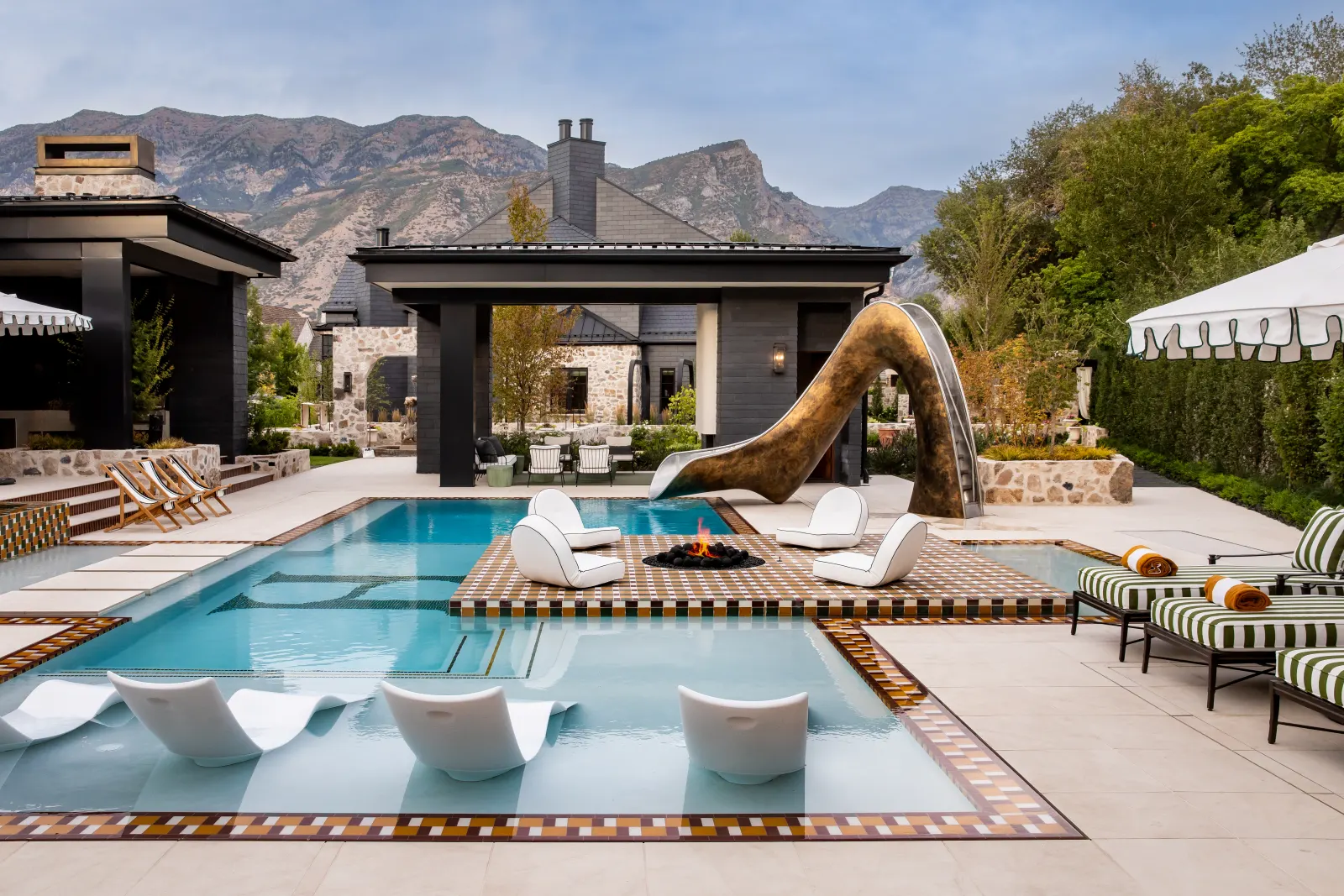 Modern Elm zero-edge pool with sun shelf and fire feature, set against the mountain backdrop at golden hour.
