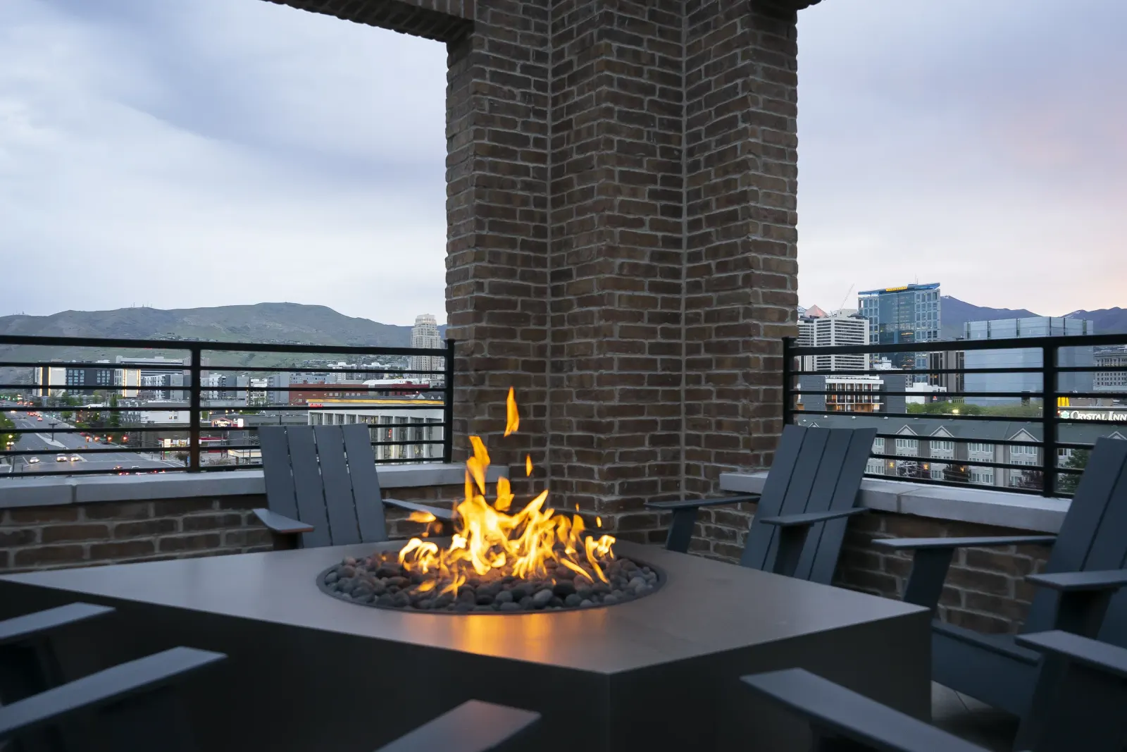 Post House courtyard at dusk with a fire pit, chimney and Adirondack seating